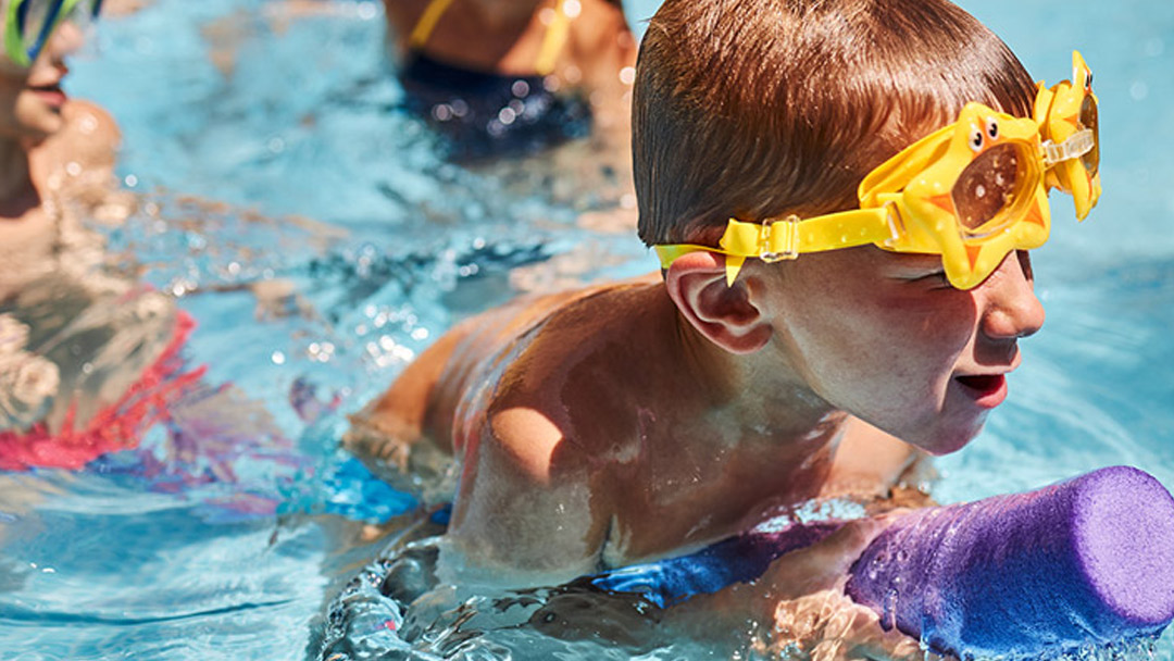 Boy in swimming pool playing with a float