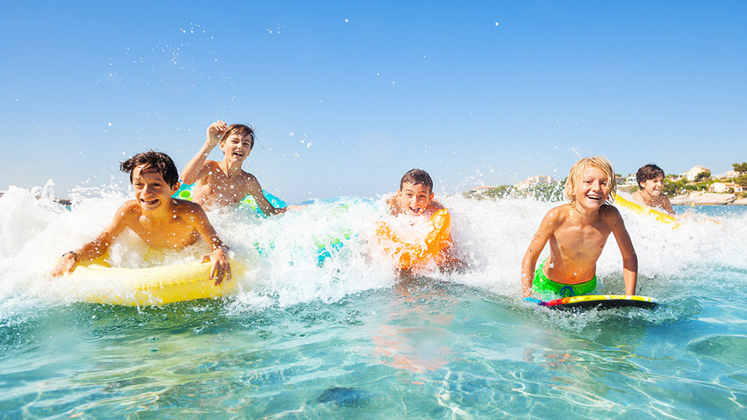 Five children playing and surfing in the waves at the beach